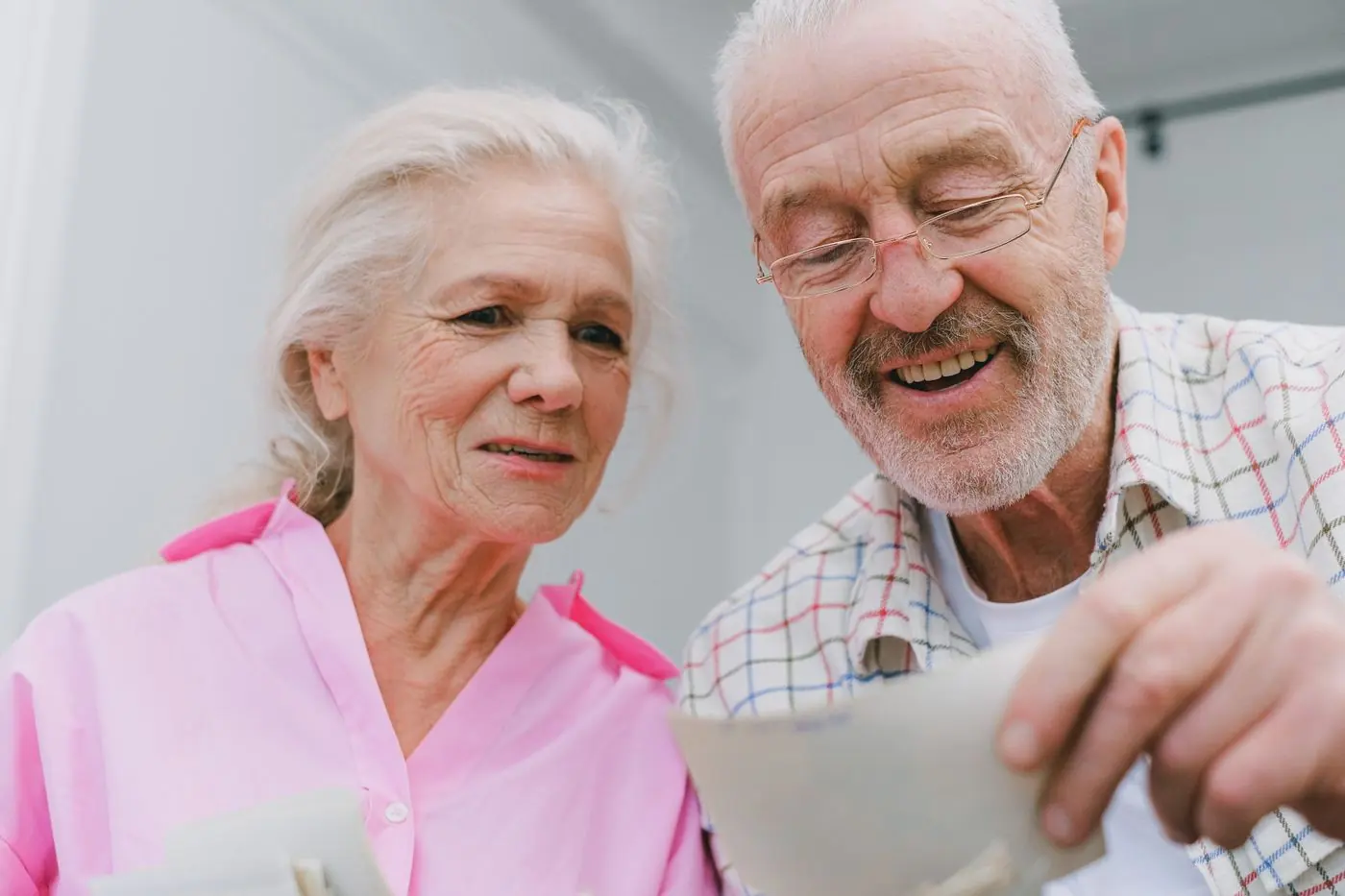 An older couple laughing as they look through old photographs