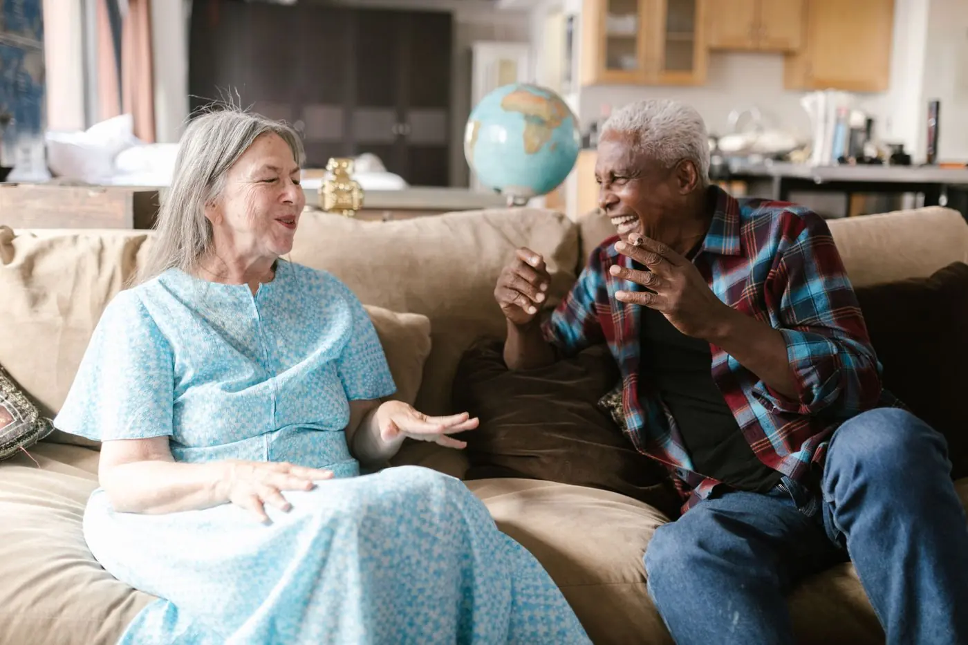 An older couple laughing together on their sofa at home