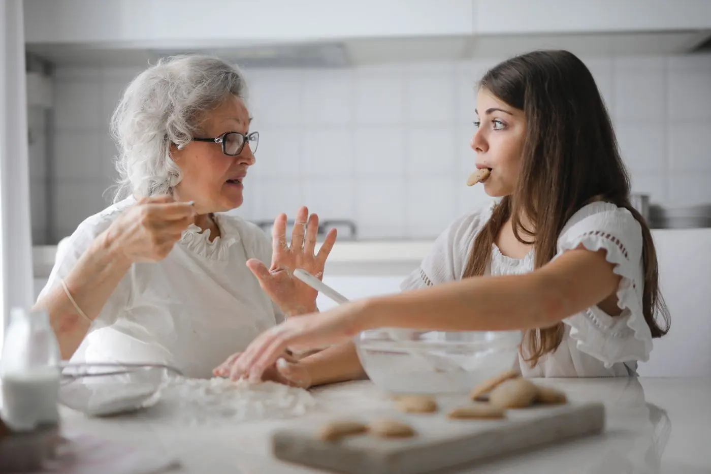 A grandmother mid-story at the kitchen table while her granddaughter listens