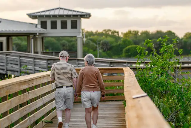 An older couple walking together along a wooden boardwalk