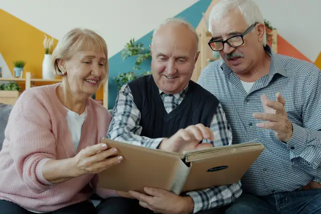 Three older friends looking through a photo album together