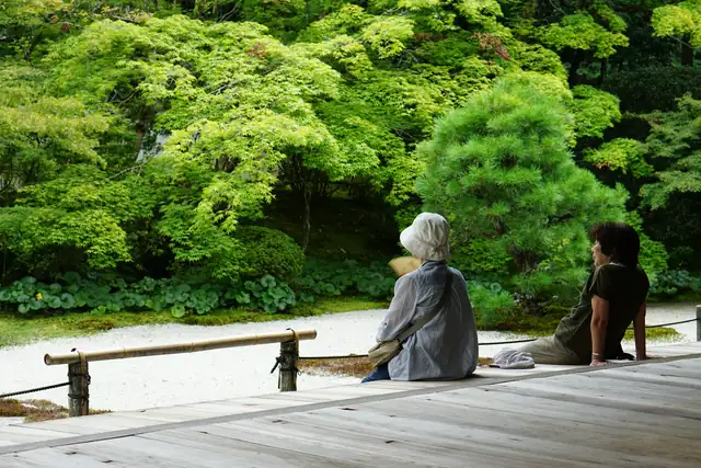 Two people sitting on a bench, looking out over a green garden