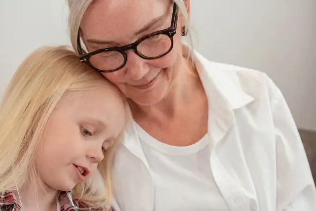 A grandmother holding her young granddaughter close as they look through a family photo album