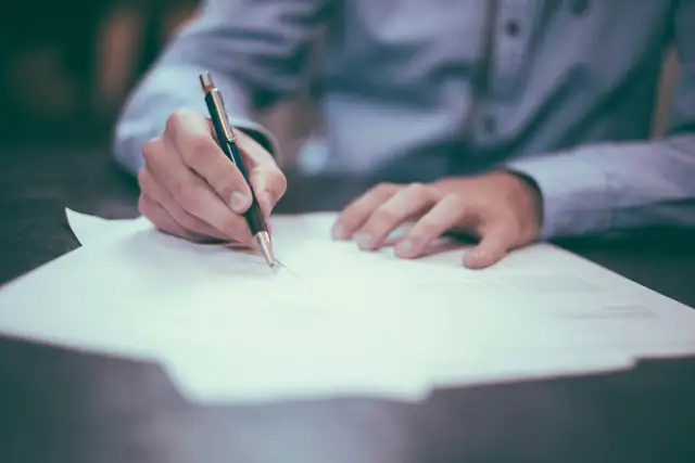 A man writing on a sheet of paper at a table