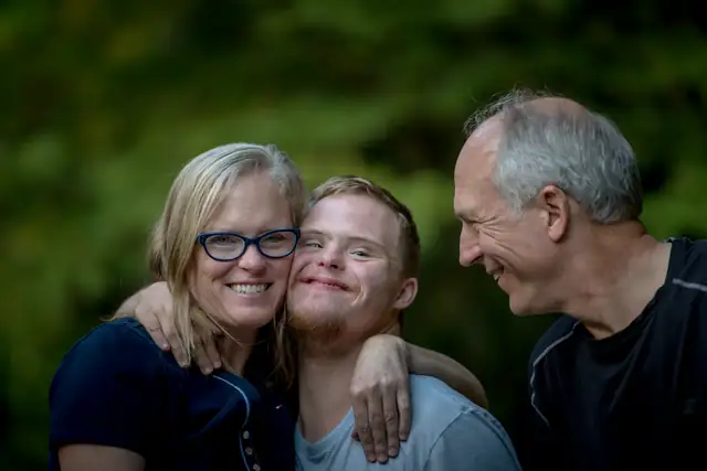 A family of three sharing a hug outdoors