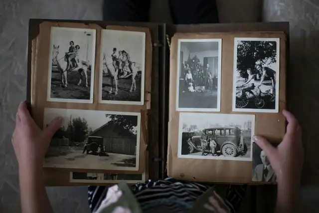 Hands opening an old family photo album of black and white photos