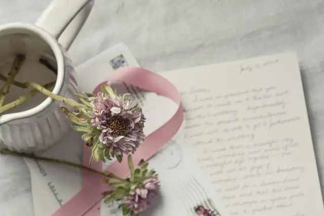 A handwritten letter with a ribbon and dried flowers