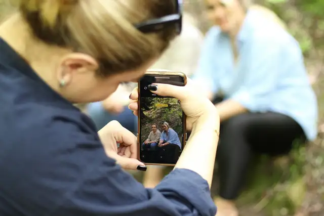A woman taking a photo of two friends with her phone